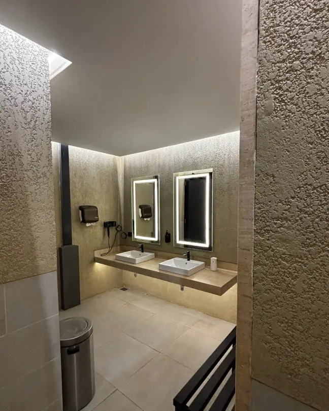 Stone washroom with lit mirrors